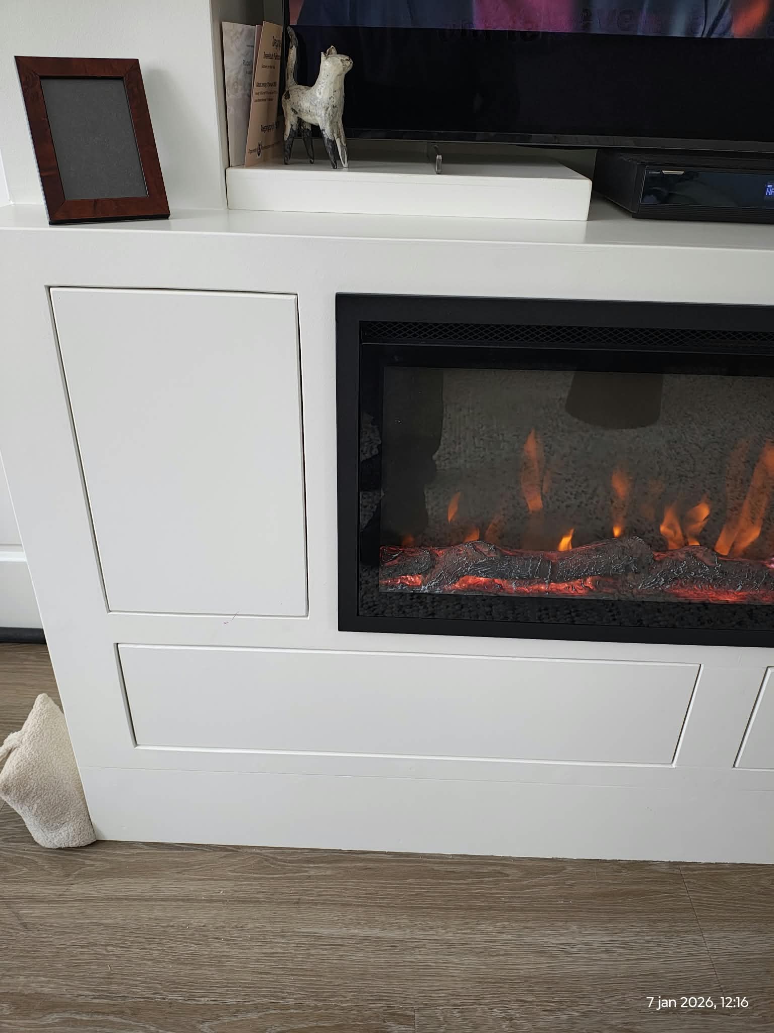 Detail van een witte maatwerk ombouw met paneeldeuren rond een elektrische haard