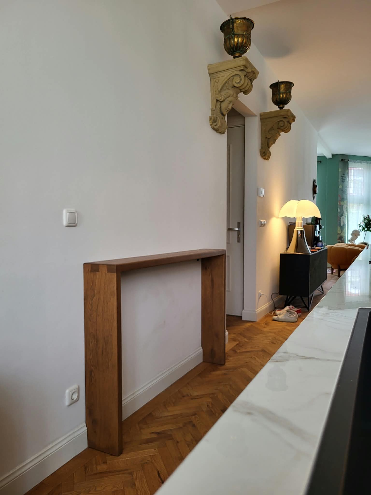 Smalle houten sidetable op maat tegen de wand in een woonhuis