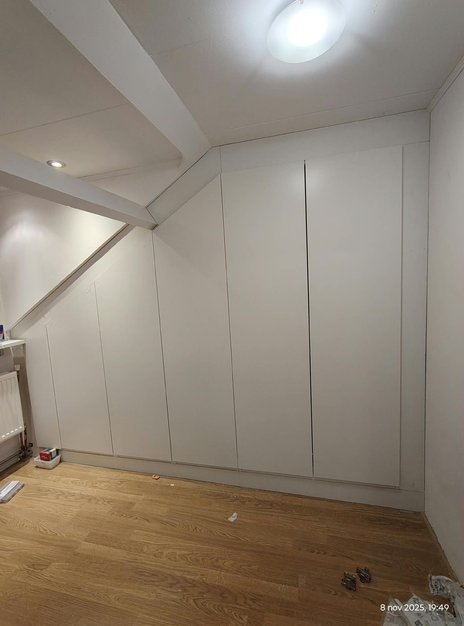 Witte kastenwand op maat die aansluit op een schuin plafond